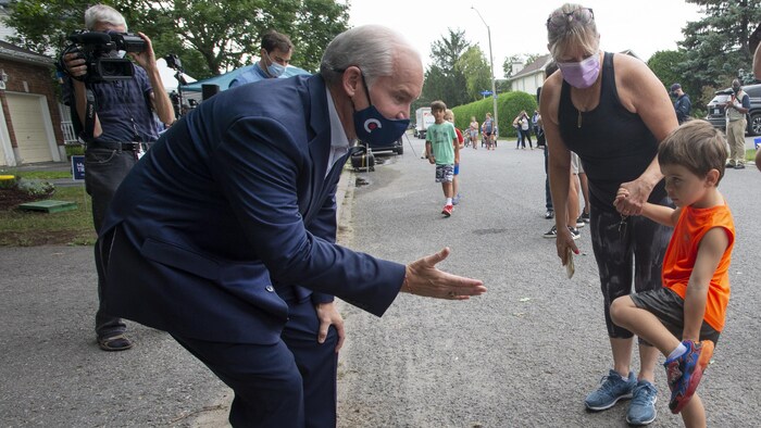Le chef conservateur Erin O'Toole tente de serrer la main à un enfant.
