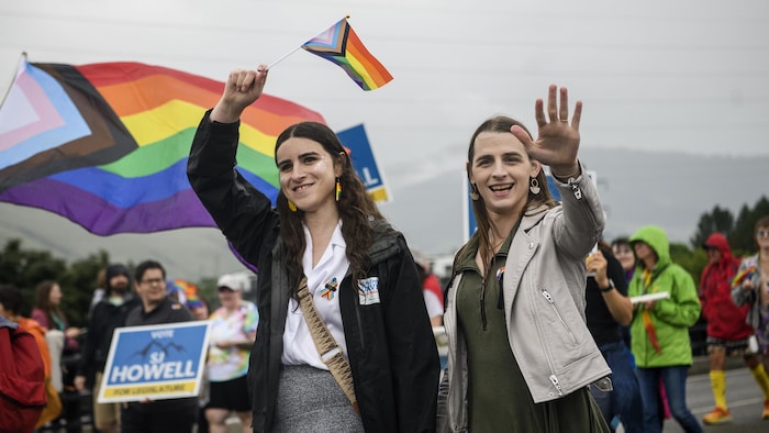 Erin Reed agite un drapeau multicolore. À droite, Zooey Zephyr salue la foule.