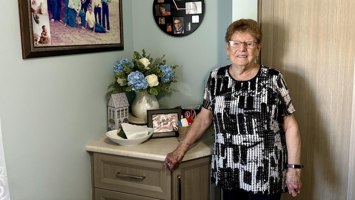 Erma Arsenault pose devant des photos de sa famille dans sa chambre. 