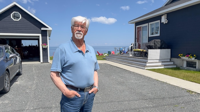 Raynald St-Laurent devant sa maison avec vue sur le fleuve.