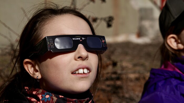 Une élève regarde l'éclipse avec ses lunettes de protection.                 
