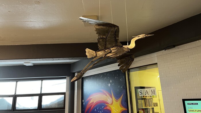 Une sculpture métallique en forme de grand héron, suspendue au plafond du Cégep de l'Abitibi-Témiscamingue.