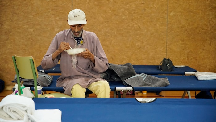 Un homme mange dans un gymnase.
