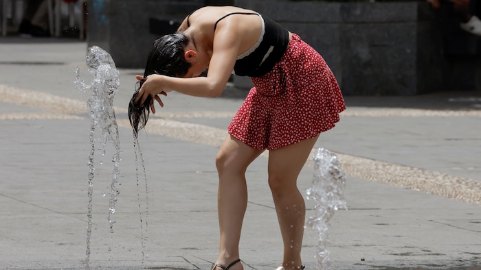 Une femme se rafraîchit grâce à une fontaine d'eau dans une rue de Cordoue, en Espagne. 
