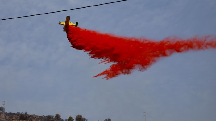 Un avion largue un produit ignifuge au-dessus d'un feu de forêt.