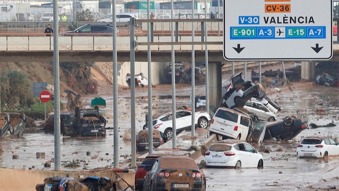 Des voitures abandonnées et pleines de boue sur une route à Valence.