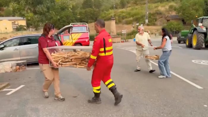 Un pompier espagnol et des responsables locaux transportent des coffrets contenant les restes des premiers rois d'Aragon après leur évacuation d'un monastère menacé par un incendie de forêt à San Juan de la Peña, en Espagne, le 13 août 2026.