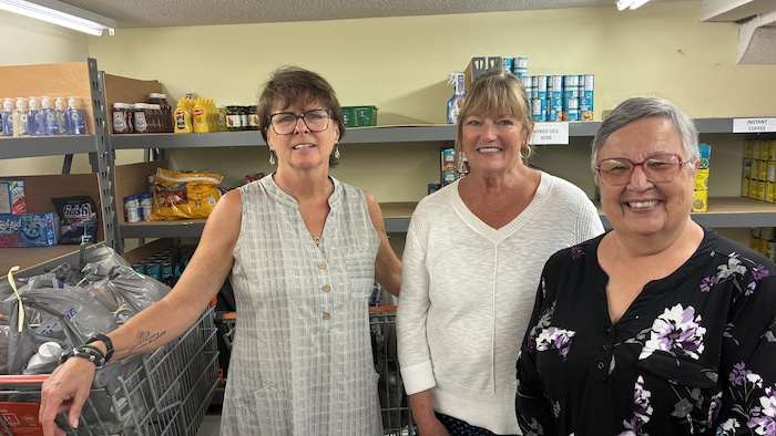  Alta Campbell, présidente de la banque alimentaire ; Judy Sullivan, secrétaire ; et Bernadette Houle, trésorière devant des denrés. 