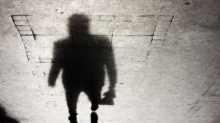 L'ombre d'une personne qui marche sur un trottoir la nuit.