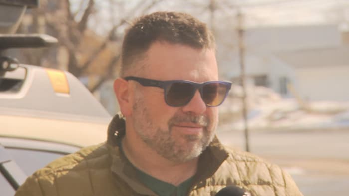 Un homme en entrevue devant son véhicule.