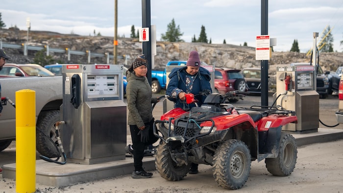 Deux femmes mettent de l'essence dans un VTT.