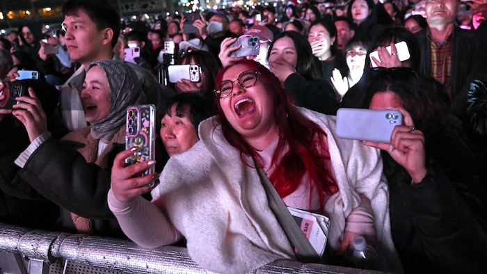 Des admirateurs de BTS regardent le concert du groupe sur un écran.
