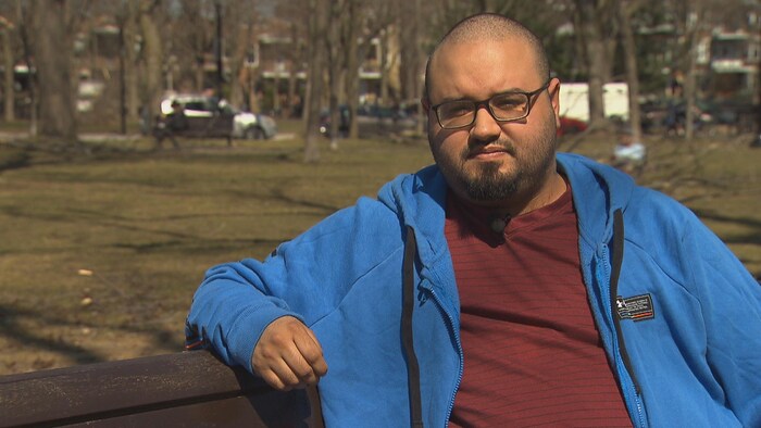 Portrait d'Esteban Torres, assis sur le banc d'un parc.