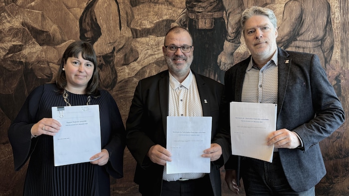 Jeanie Caron, Michel Desbiens, et François Corriveau posent devant la caméra en tenant les états financiers imprimés.