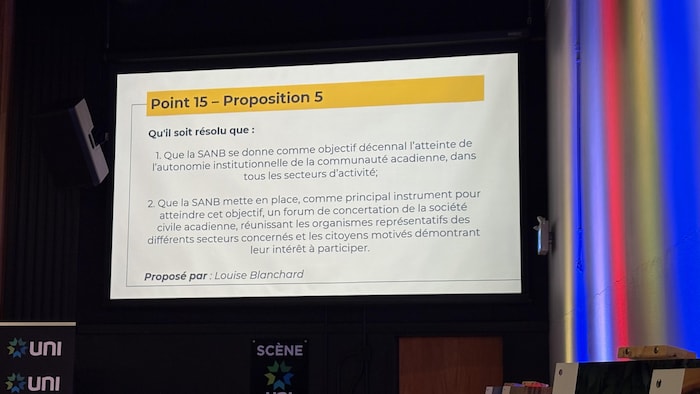 Un document intitulé «Point 15, proposition 5» est projeté sur grand écran dans une salle de conférence.