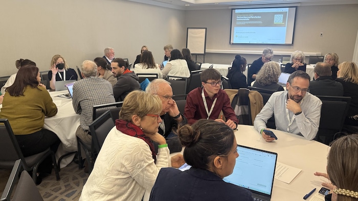 Des participants au congrès réunis dans une salle, assis en petits groupes et discutant.
