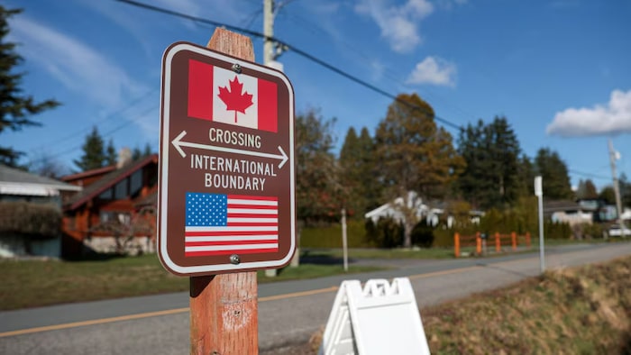 Panneau indicatif de la frontière terrestre entre les États-Unis et le Canada dans un cadre bucolique.