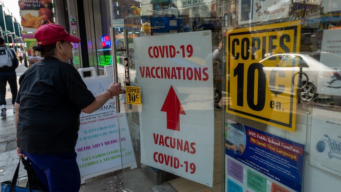 Une publicité pour les vaccins contre la COVID-19 dans la vitrine d'un commerce.