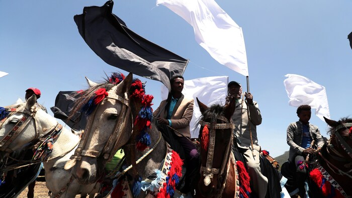 Des hommes sur des chevaux portant des drapeaux.