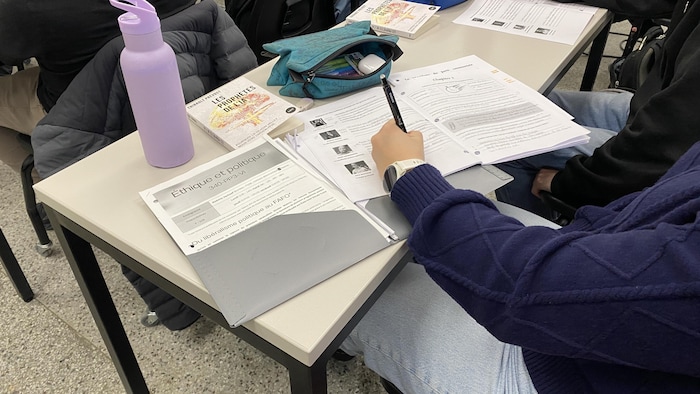 Une étudiante écrit dans ses notes de cours.