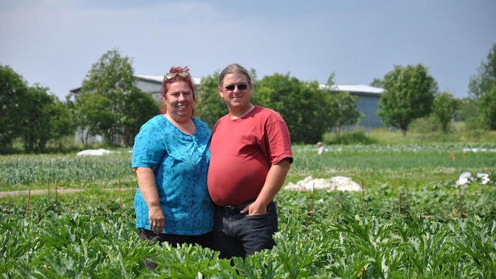 Le couple sourit dans un champ de courges.
