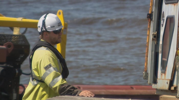 Un homme avec une veste jaune et casque blanc sur un site de construction.