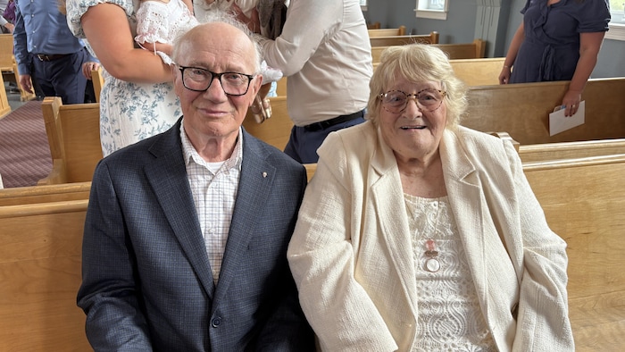 Étienne et Yvonne Haché posent pour la photo assis sur un banc d'église