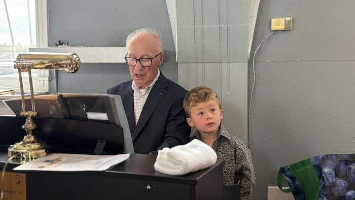 Un jeune garçon aux côtés d'Étienne Haché sur un banc derrière l'orgue