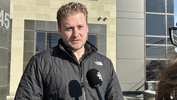 Un homme en entrevue avec une journaliste devant le palais de justice.