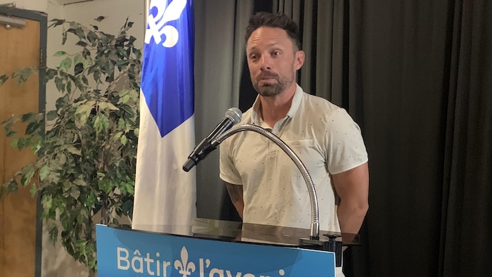 Étienne Ricard, debout derrière un lutrin, fait une petite allocution.