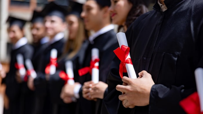 Une rangée d'étudiants universitaires tenant leur diplôme.