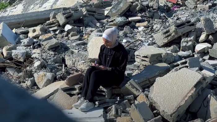 Meera Falyouna assise sur un tas de décombres,