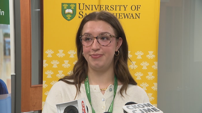 Molly Morris répond aux questions des journalistes, debout derrière un pupitre muni de microphones.
