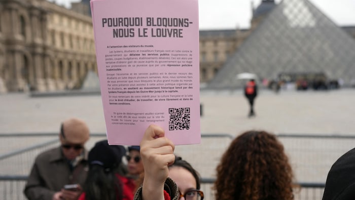Une manifestante brandit une pancarte informant les visiteurs de la fermeture du musée.