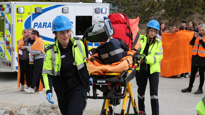 Des étudiantes en soins paramédicaux qui tirent une civière pour assister les personnes dans le besoin.