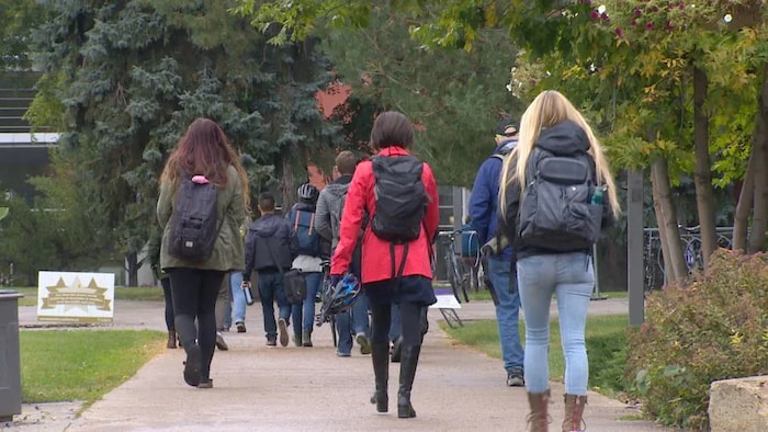 Des étudiants portant des sacs à dos marchent sur le campus de l'Université de Calgary.