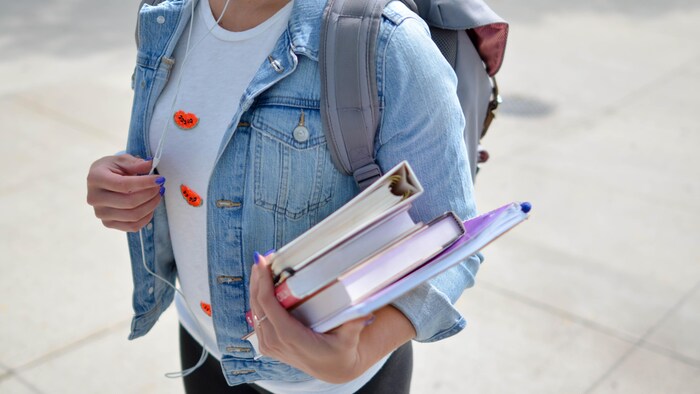 Une étudiante tient des livres.
