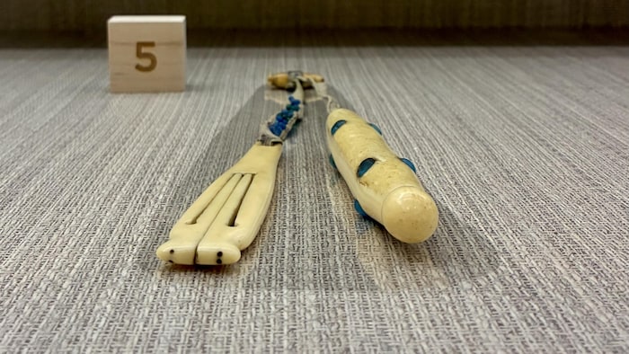 Cet étui à aiguilles du XIXe siècle, sculpté dans de l'ivoire de morse par un artisan iñupiat, est décoré de perles bleues russes acquises par le troc.