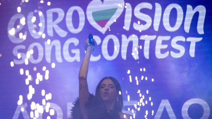 La chanteuse tient son micro dans les airs sur scène.