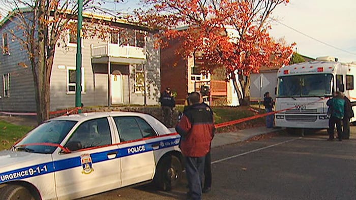 Image d'archive de véhicules de police et d'un périmètre de sécurité autour de la maison.