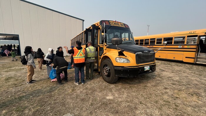 Des personnes entrent dans un autobus d'écoliers.