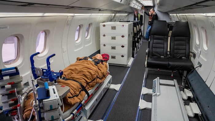 Une civière est fixée dans un avion.