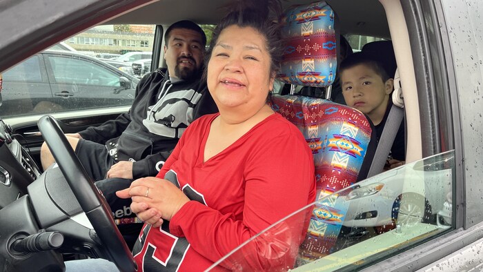 Une femme accompagnée de sa famille est souriante.