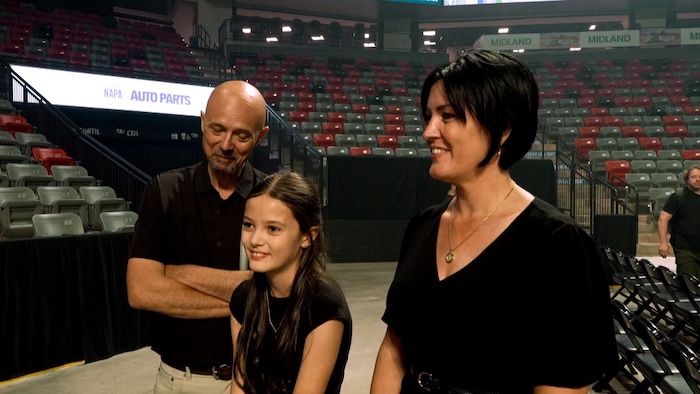 Un couple et une préadolescente au milieu d'un aréna vide.