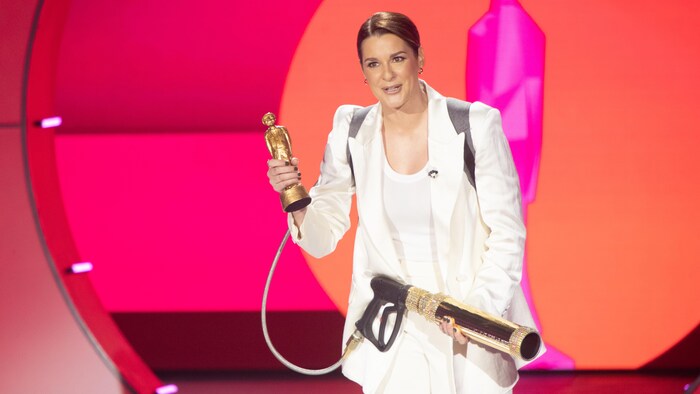 Une femme vêtue de blanc tient un lance-trophées. 