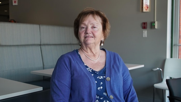 Portrait d'Evelyn Dutrisac assise dans une salle.