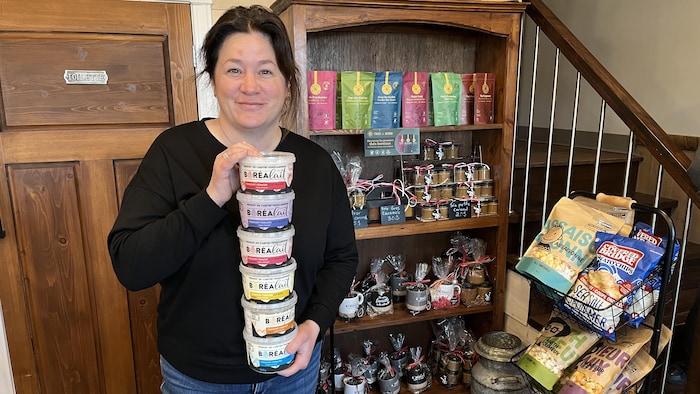Evelyne Rancourt tient six contenant de yogourt de différentes saveurs empilés dans ses mains.