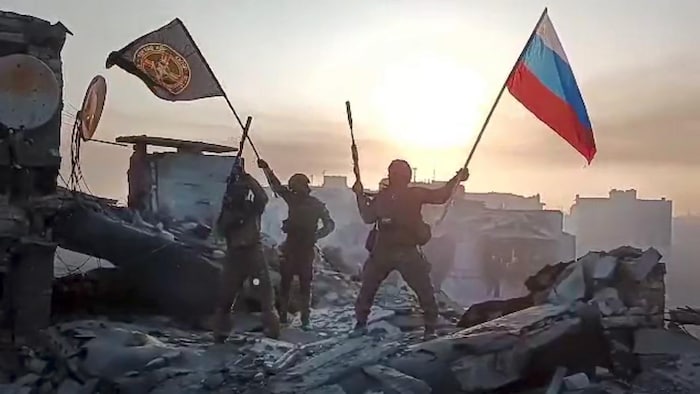 Des soldats brandissent des drapeaux du groupe Wagner et de la Russie.