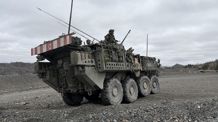 Un soldat équipé d’un fusil d’assaut monte la garde dans la tourelle d’un véhicule blindé dans le cadre d’un exercice militaire se tenant dans une mine à ciel ouvert.
