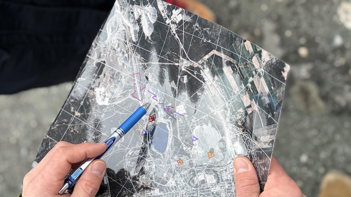 Plan rapproché sur une carte composée d’une image satellite. Une main indique un point sur la carte à l’aide d’un stylo.